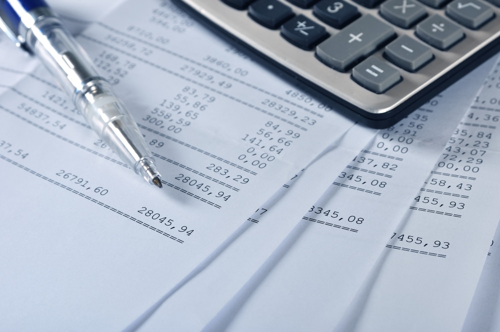 A calculator sits next to a stack of financial statements.