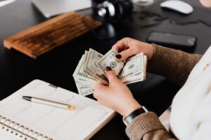 A person counting money with a notepad and pen in front of her